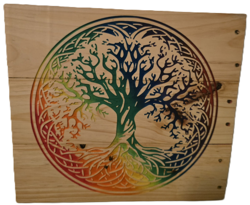 Rainbow tree of life design carved on a wooden panel, featuring vibrant colors transitioning from green to orange.