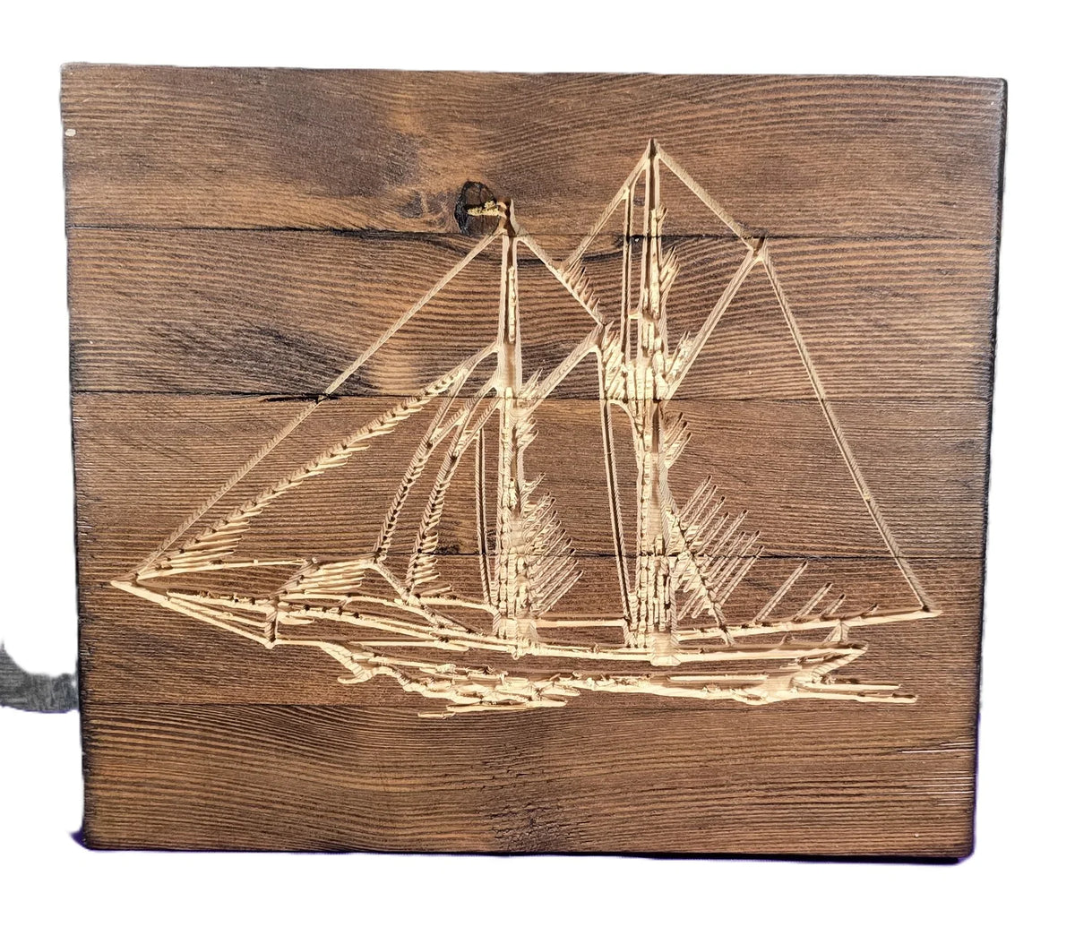 Carved wooden sailboat design on a textured brown wood panel.