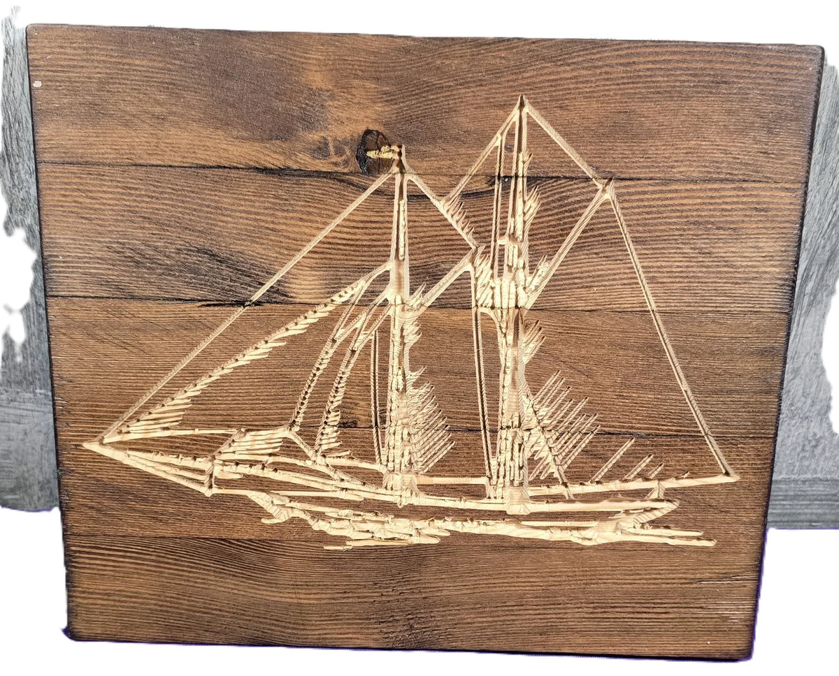 Carved wooden sailboat design on a rustic wood panel with visible grain and texture.