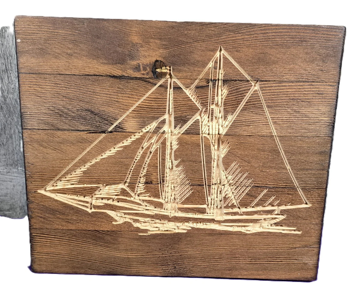 Wooden plaque featuring a detailed engraving of a sailboat with two masts on a rustic wood background.