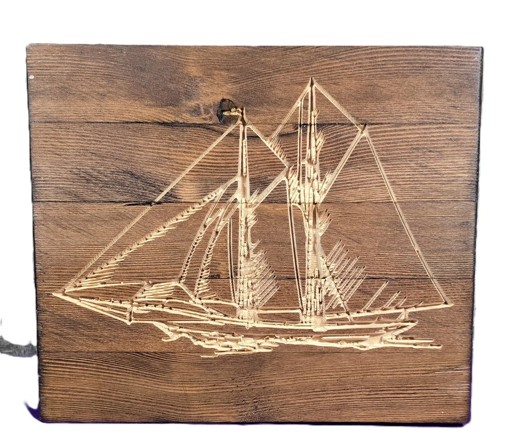 Sailboat engraving on a wooden plaque with detailed rigging and sails, set against a rustic wood background.