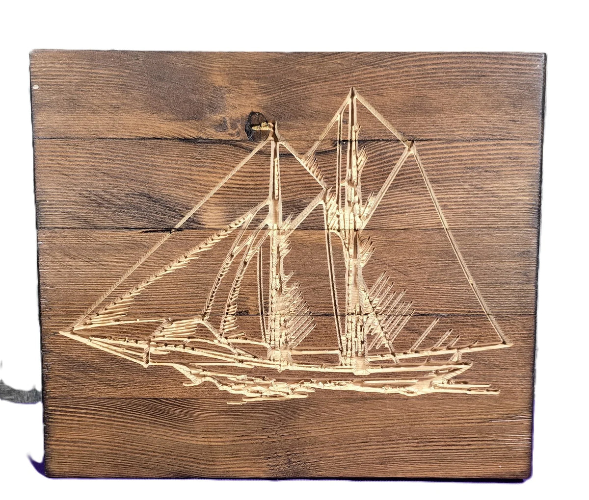 Sailboat engraving on a wooden plaque with detailed rigging and sails, set against a rustic wood background.