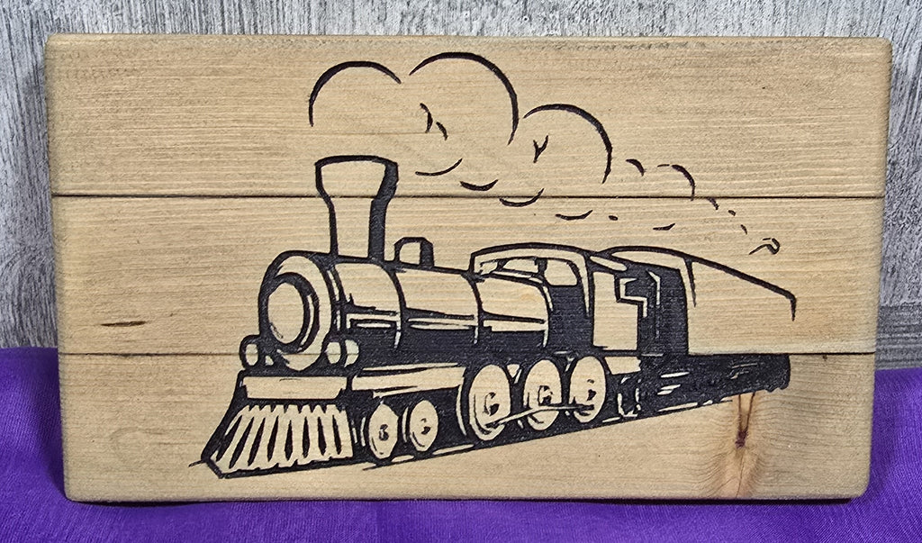 Black train illustration on a wooden plank with a textured background and purple fabric underneath.