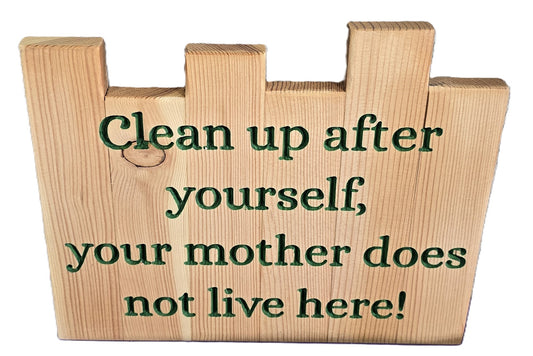 Wooden sign with green text stating "Clean up after yourself, your mother does not live here!" on a natural wood background.