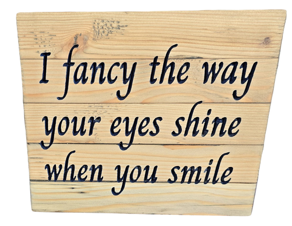 Wooden sign with engraved text: "I fancy the way your eyes shine when you smile.