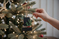 TK Wood Designs handcrafted matte black wooden holiday ornament with greenery and red berries on a Christmas tree.