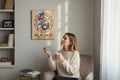 TK Wood Designs Capricorn zodiac sign engraved wooden wall art hanging on a wall above a woman in a cozy living room.