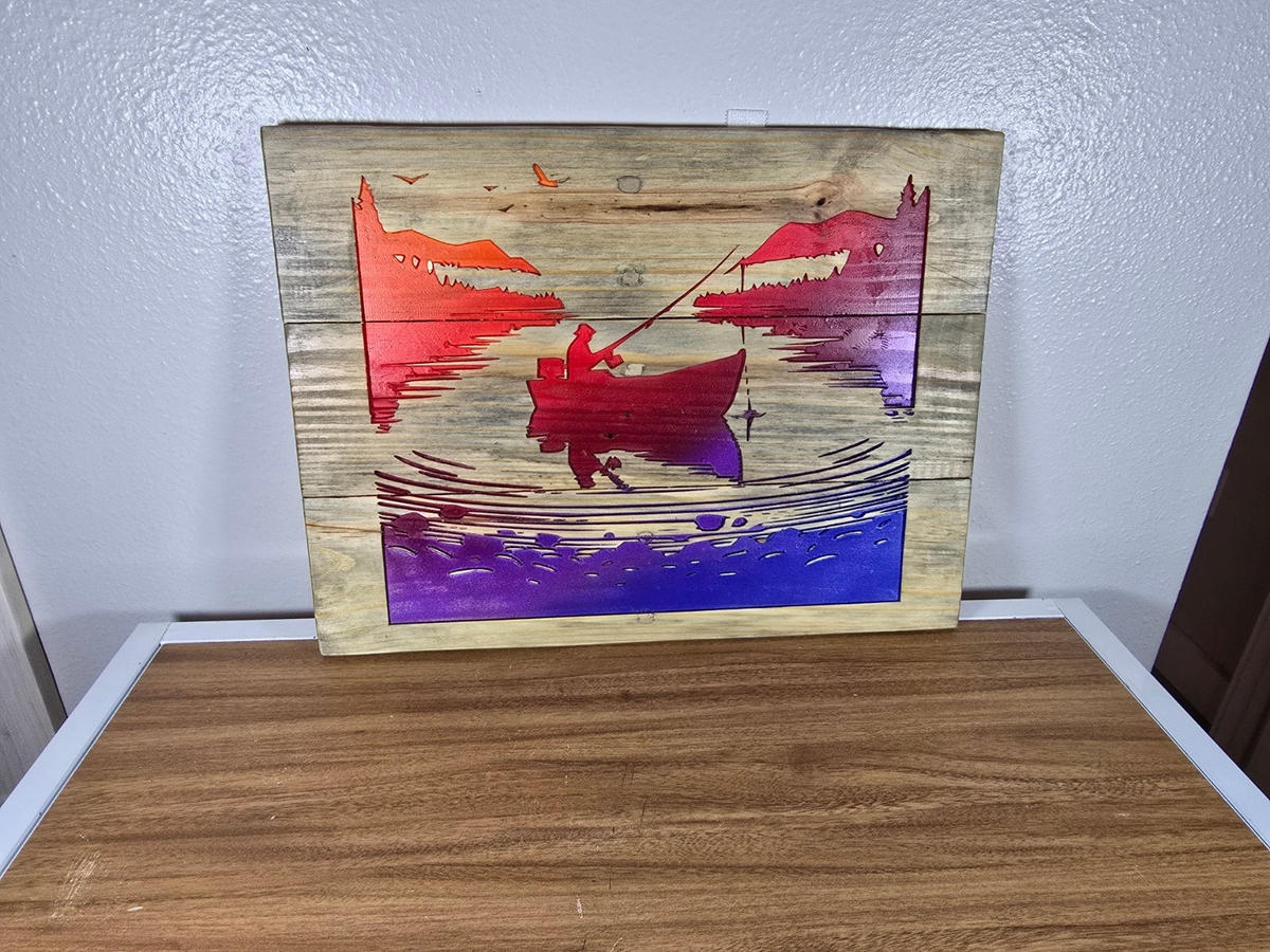 TK Wood Designs rustic wooden wall art featuring a fisherman in a boat with a vibrant orange, red, and purple sunset.