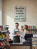 TK Wood Designs rustic wood sign with black text reading "You don't have to be crazy to work here" and green text reading "WE WILL TRAIN YOU!"