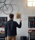 TK Wood Designs Grim Reaper wood wall art with black graphic giving the number one sign, displayed in a garage setting.