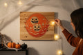 TK Wood Designs rustic wood sign with carved Halloween pumpkins, moon, and spooky trees in orange and black.