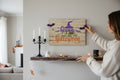 TK Wood Designs rustic wooden Happy Halloween wall sign with witch hat and bat accents held by a woman on a shelf.