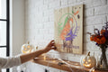 TK Wood Designs rustic wooden Happy Halloween sign with a colorful jack-o'-lantern and witch hat graphic on a brick wall