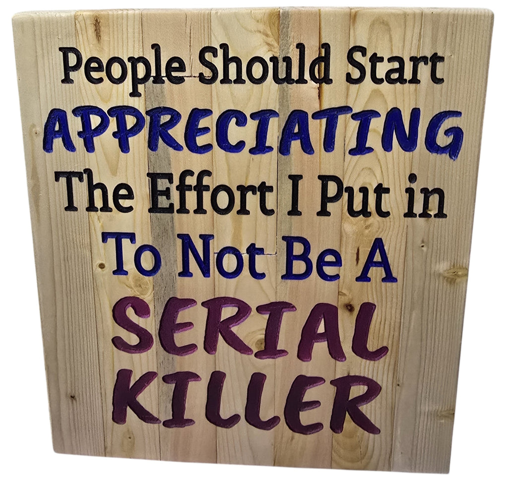 TK Wood Designs wooden sign with humorous quote "People Should Start Appreciating The Effort I Put in To Not Be A SERIAL KILLER" in black, blue, and purple lettering.