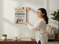 Woman hanging a TK Wood Designs rustic wooden wall sign with humorous text on a white living room wall.