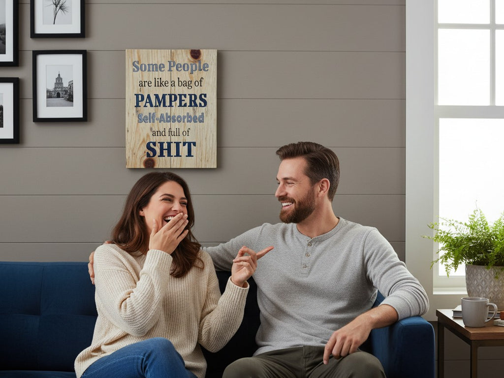 TK Wood Designs humorous wooden wall sign with witty text hanging above a laughing couple on a blue sofa.