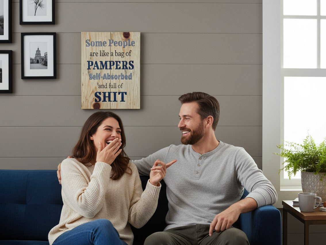 TK Wood Designs humorous wooden wall sign with witty text hanging above a laughing couple on a blue sofa.
