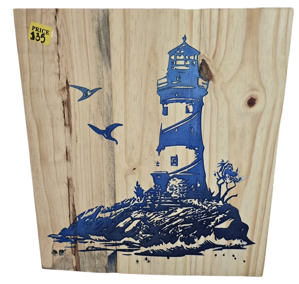 TK Wood Designs natural wood wall art featuring a blue lighthouse on a rocky shore with two seagulls. Rustic coastal decor.