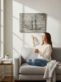 A woman sitting on a sofa admiring TK Wood Designs handcrafted nautical sailboat wall art on a rustic wood panel.