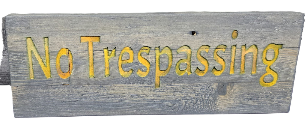TK Wood Designs handcrafted wooden sign with routed yellow lettering reading "No Trespassing" on a distressed grey wood background.