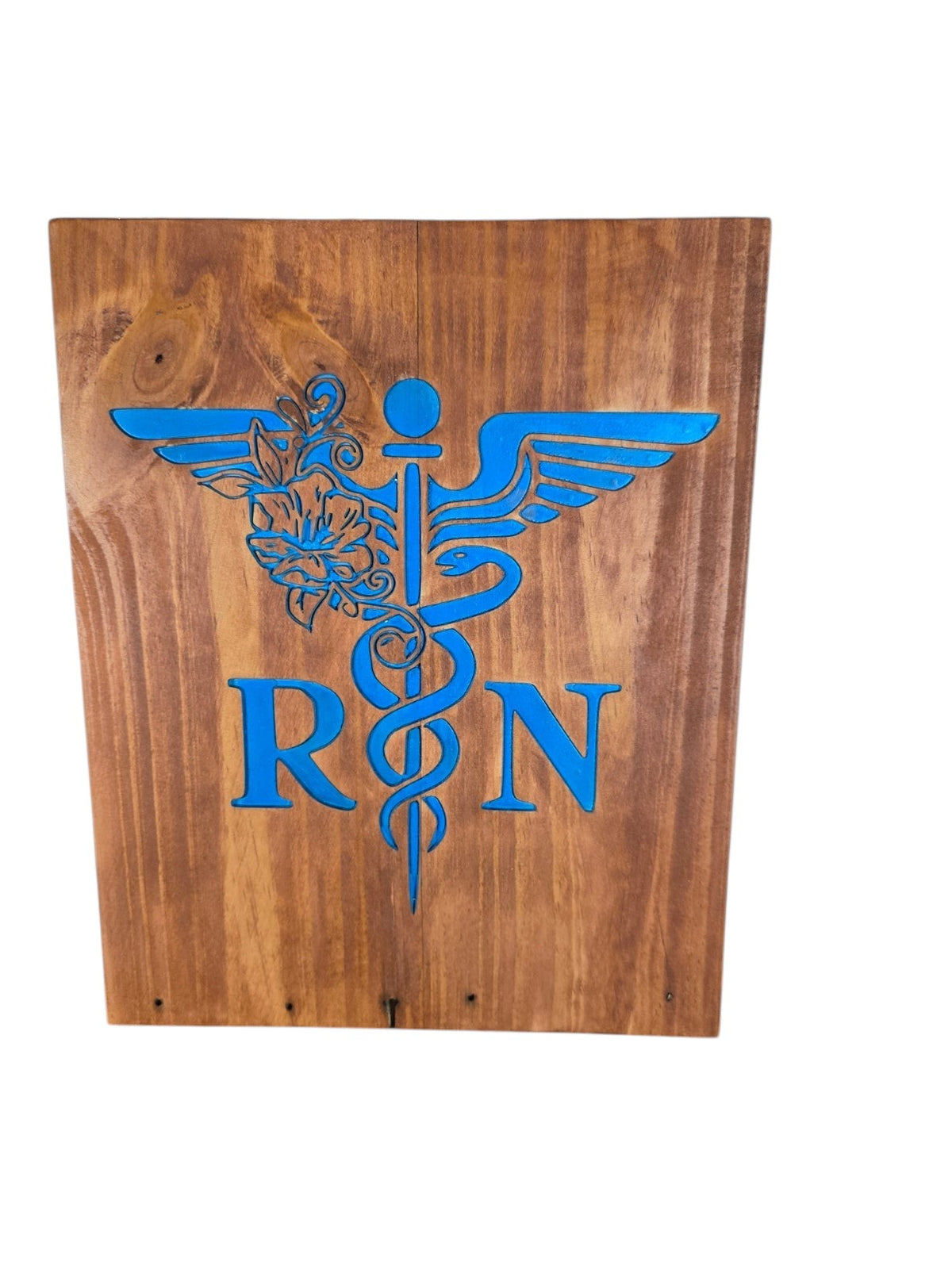 TK Wood Designs wooden RN sign featuring a blue caduceus medical symbol with floral accents on a stained wood board.