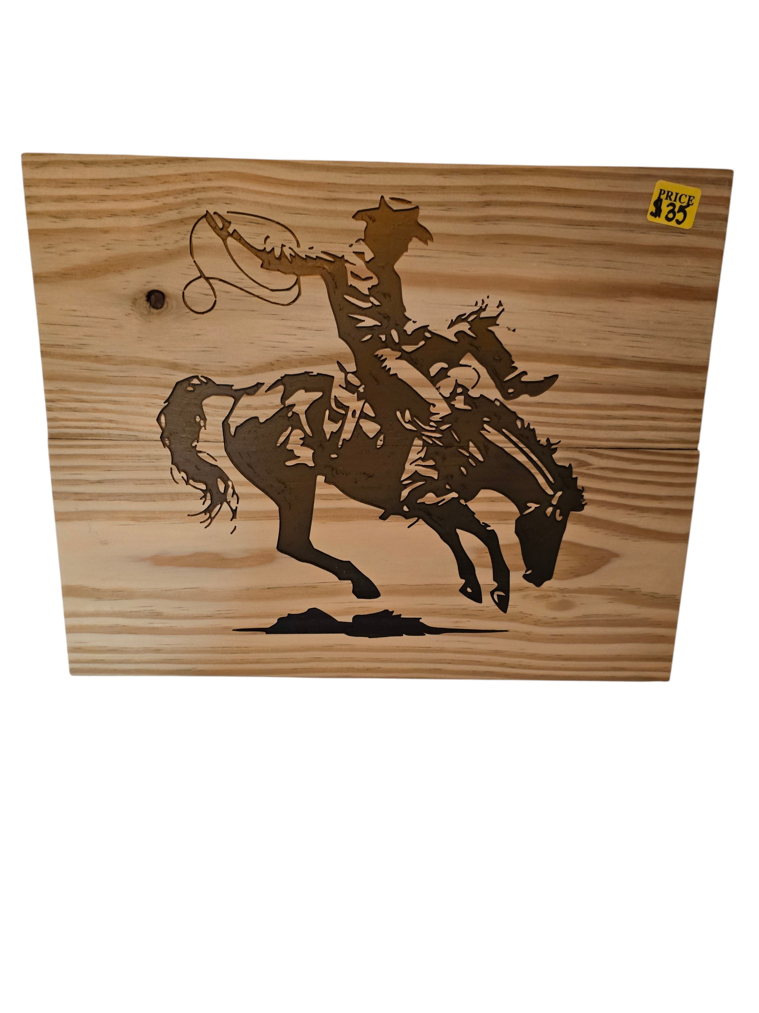 TK Wood Designs natural wood art of a cowboy on a bucking bronco, capturing rodeo action. Rustic silhouette.