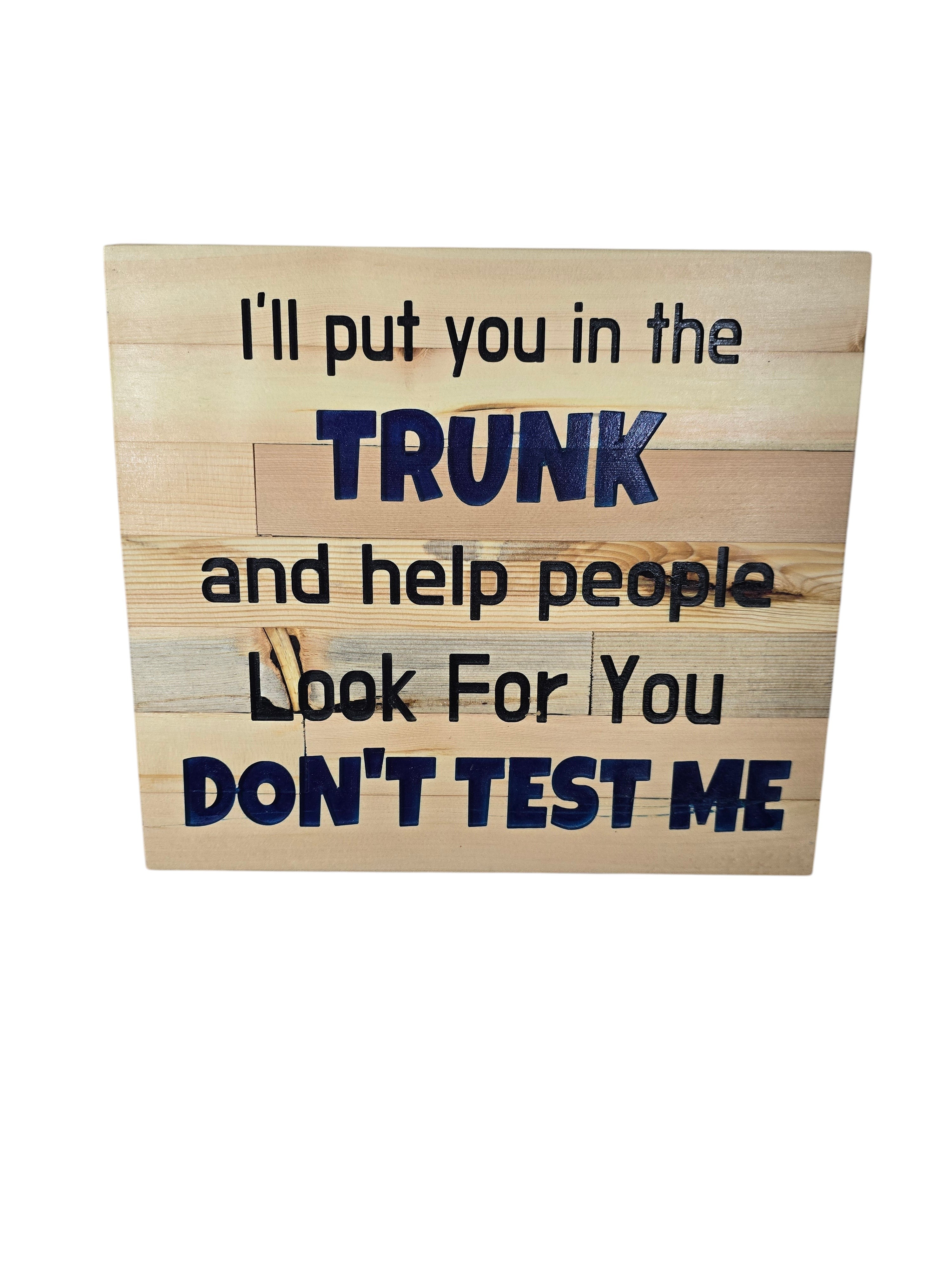 TK Wood Designs natural wood wall art with bold navy blue text reading "I'll put you in the TRUNK and help people look for you DON'T TEST ME".