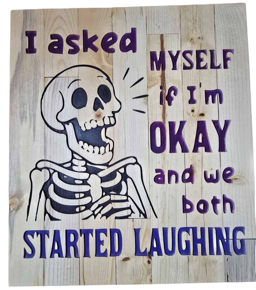 TK Wood Designs reclaimed wood sign with a skeleton graphic and purple text that reads "I asked MYSELF if I'm OKAY and we both STARTED LAUGHING."