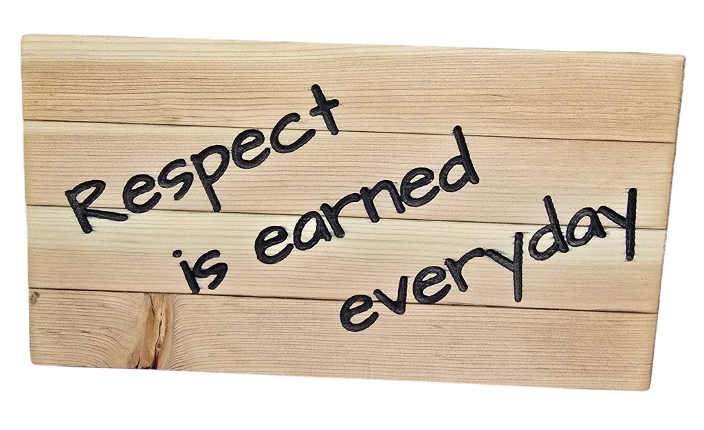 TK Wood Designs wooden sign with black text reading "Respect is earned everyday". Natural wood planks.