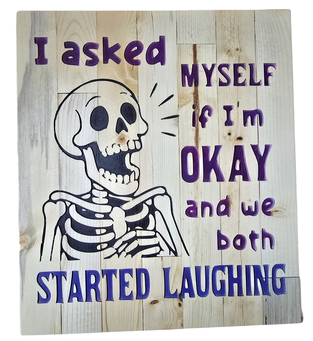 TK Wood Designs reclaimed wood sign with a skeleton graphic and purple text that reads "I asked MYSELF if I'm OKAY and we both STARTED LAUGHING."