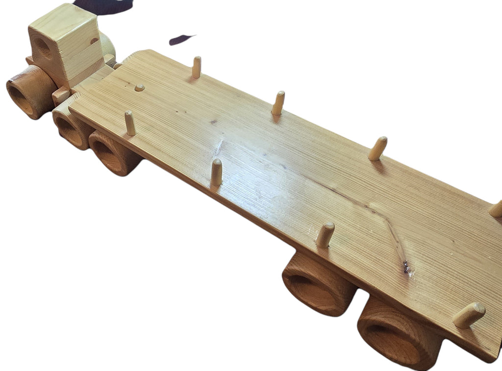 TK Wood Designs natural wood flatbed semi-truck toy with wooden wheels and cargo stakes.