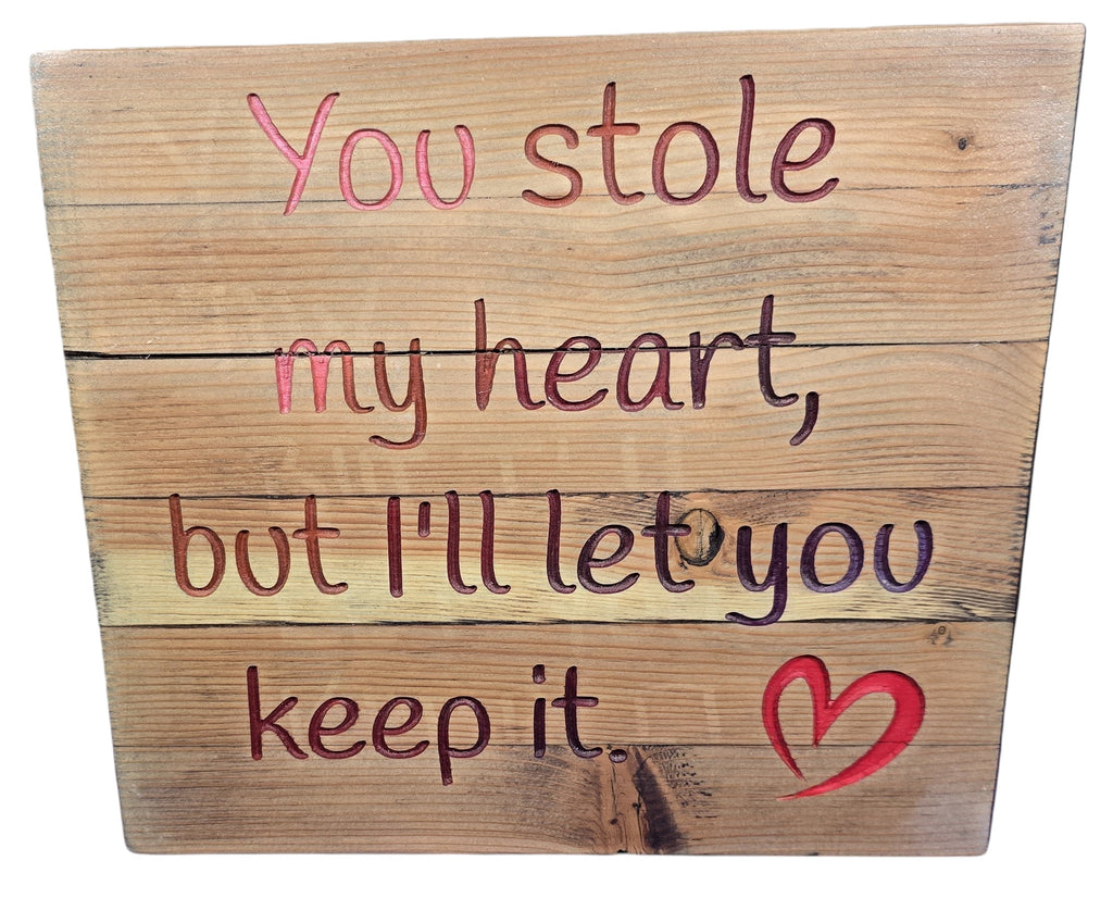 TK Wood Designs natural wood sign with carved lettering that reads "You stole my heart, but I'll let you keep it." Features a red heart accent.